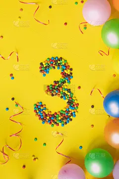 黄色背景上有彩色气球的3号糖果。生日的概念。