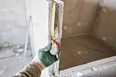 建筑工人用卷尺测量石膏板。公寓的内墙使用带槽脊的石膏混凝土板。企口石膏块