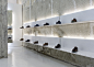 White shelves hang from concrete walls at shoe shop by Elia Nedkov