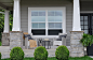 two white single-hung windows that connect a traditional front porch with the gray home interior