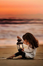 Young girl on the beach near sundown with her lantern: 