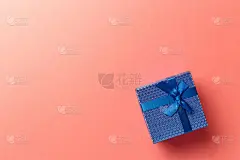 以珊瑚为背景，配以蓝丝带的蓝色礼盒。前视图。平的。副本的空间。彩色的背景。最小圣诞新年创意概念。时尚