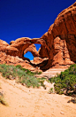 This may contain: an arch shaped rock formation in the desert