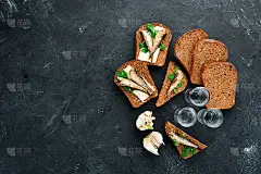 三明治加小虾和伏特加。小人物在油中。在黑色的背景上。前视图。免费空间。