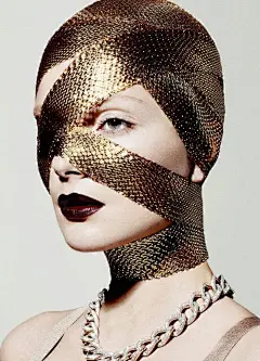 This may contain: a woman with gold makeup and chains on her face