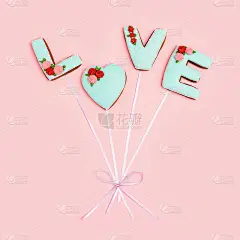 画在姜饼的爱字的形状，气球用丝带连接在粉红色的背景。情人节最简单的贺卡。