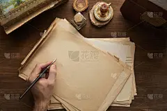 在绘画、蜡烛和旧收音机旁边的木制桌子上，人们把钢笔高高地放在复古纸上的剪影