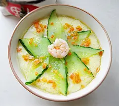 黄瓜虾仁蒸蛋】食材：鸡蛋60g、芝麻油适量、盐适量、黄瓜适量、虾仁适量、水适量、胡萝卜适量
1)漂亮的双黄蛋2)加入芝麻油和盐
3)加入大半碗温开水搅打均匀，放入蒸锅大火烧开4)黄瓜切薄片，胡萝卜切碎5)蒸汽上来后3分钟放入黄瓜片6)加入虾仁，撒上胡萝卜碎。盖盖再蒸2分钟