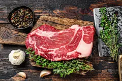 生黑安格斯上等牛肉卷牛排在切板与切肉刀。深色木制背景。俯视图