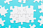 Top view of white jigsaw puzzle piece on blue backdrop