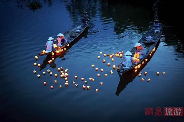 越南灯船穿着越式旗袍的女孩子正往河中放漂流的蜡烛为死去的人们祈祷