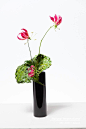 This may contain: a black vase filled with flowers on top of a table