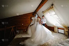 穿着婚纱的新娘从她头上的面纱走向新郎。初次见面的新婚夫妇或新婚之夜的新婚夫妇。蜜月。早上在家里。
