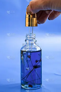 滴管玻璃瓶模型。油性液滴从化妆品吸管上落在蓝色背景上。年度颜色，