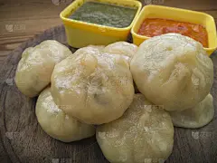 木盘子上放着红绿酸辣酱的饺子。