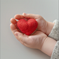 coloyou_A_babys_hand_holding_a_close-up_of_a_red_heart_on_a_whi_4f8a45de-78b7-432b-b57e-8a10b1089f34