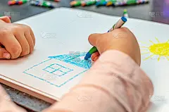 房子的梦想的概念。孩子用彩色铅笔在纸上画一座房子。梦想着自己的家