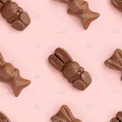 复活节兔子形状的牛奶巧克力糖果在粉红色的背景上排列成行。宗教节日作文，兔子图案为祝贺贺卡。庆祝基督星