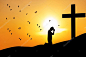 一个人在十字架下祈祷的日出或日落的轮廓