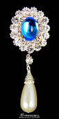  这枚胸针叫玛丽费奥多罗芙娜皇后的蓝宝石胸针（The Empress Marie Feodorovna's Sapphire Brooch）中间是颗蛋面蓝宝石，下面垂着一颗梨形的珍珠，1928年被玛丽女王买了回来，现在归女王所有，不过女王还真没怎么戴过