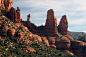 This may contain: red rock formations in the desert with trees and bushes on each side, under a blue sky