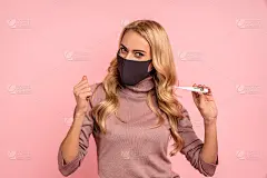 在大流行隔离期间，一名因感染冠状病毒而被治愈的快乐妇女穿着罩衫，戴着无菌口罩，以避免感染covid-