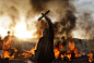 An activist holds a cross in front of a burning barricade during evictions at the Dale Farm travellers site, near Basildon England, 30 miles (50 kilometers) east of London. Police in riot gear used sledgehammers to clear the way for the eviction of a comm