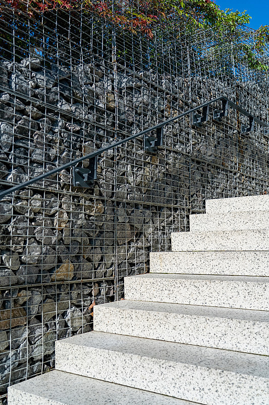 花岗岩楼梯与栅栏的石头在金属网格。现代混...