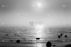 美丽的风景在海边与石头在水中，透过雾，太阳和它的反射可见