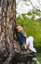 可爱的学龄前小女孩穿着黑色皮夹克坐在一棵老大树下