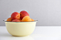 Ripe apricots in yellow bowl on white table