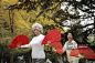 Senior women dancing with red fans in a park.