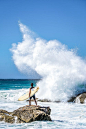 Person Holding Surfboard Standing On Rock 