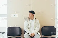 一个年轻的亚洲人坐在候诊室的走廊里等待面试或会议。学生或参赛者在接待处考试或人事。男病人在医院诊所办