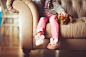 Girl in Grey Jacket and Pink Jeans Sitting in Grey Sofa Holding a Brown Short Coated Puppy