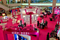 This may contain: the interior of a shopping mall with pink carpet and white walls, people walking around