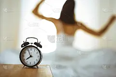 女人在床上伸开双手醒来后，太阳耀斑。深色头发的女人进入一个愉快和放松的一天后，睡了一个好觉和后视图。