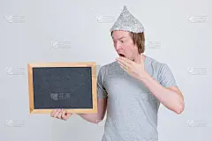 戴着锡纸帽的年轻人拿着黑板，看起来很震惊