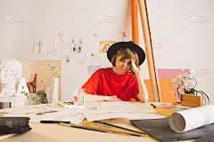 悲伤的女孩插画艺术家抓着头坐在工作室的桌子上。冷漠、沮丧和创意危机的状态