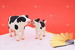 牛父母和孩子的泥塑。一个日本风格的形象，金色的扇子和红色的日本纸。