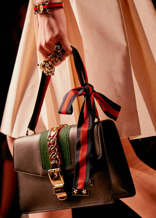 sylvie的柔美外形罗缎质地织带肩带和闪闪发光的军旅风格金属配件令肩