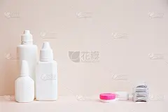 浅粉色背景上的隐形眼镜和隐形眼镜护理产品