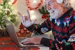 圣诞节时，满脸胡须的快乐老男人在家里视频通话。用笔记本电脑比划乐观微笑的新年