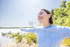 自由快乐的女人在森林湖上享受大自然。美丽的女孩在外面。自由概念。美丽迷人的女孩在天空和太阳。太阳光。