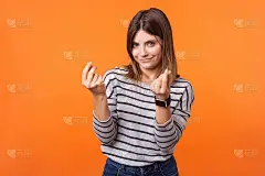 聪明美丽的女人肖像与棕色头发在长袖条纹衬衫。室内工作室拍摄孤立的橙色背景