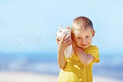 Listen to the sea shellSmiling kid on the beach listen to the sounds of the sea shell. Vibrant and hot summer colors, sunshine outdoor.