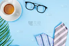 快乐的父亲节背景概念与蓝色和粉色领带，眼镜，报纸，树叶和杯茶在蓝色背景与文本复制空间。