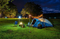 Photo camping tent and outdoor kitchen equipment at night in the park.