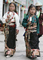 Tibetan sisters in traditional costume walk on a street in Yushu, west