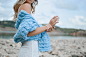 A young woman with a blue knit scarf standing on a beach